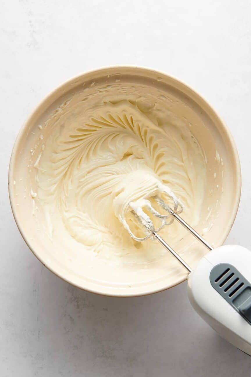 cheesecake filling batter in a large bowl with an electric mixer