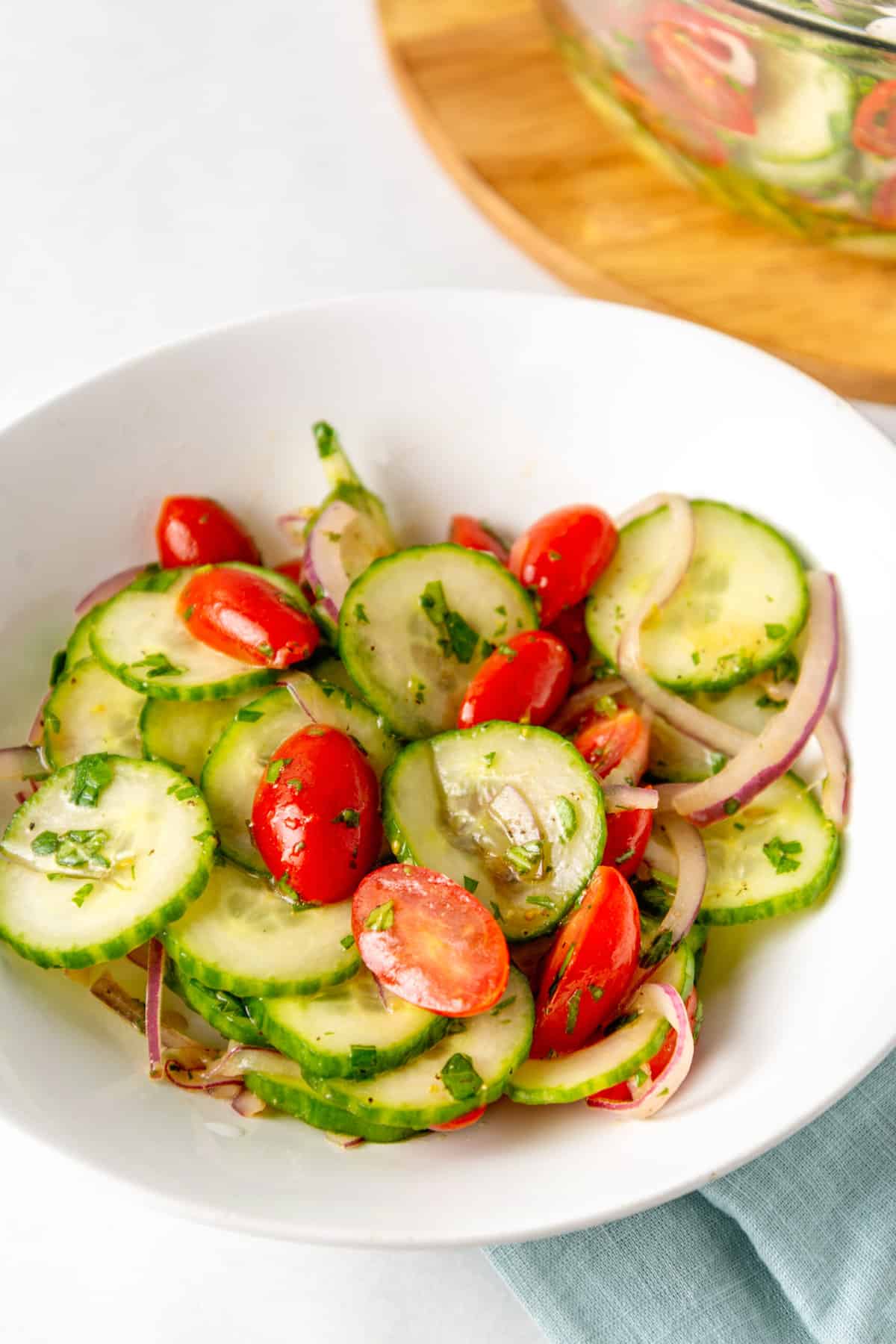 close up image of a white shallow bowl of cucumber tomato salad