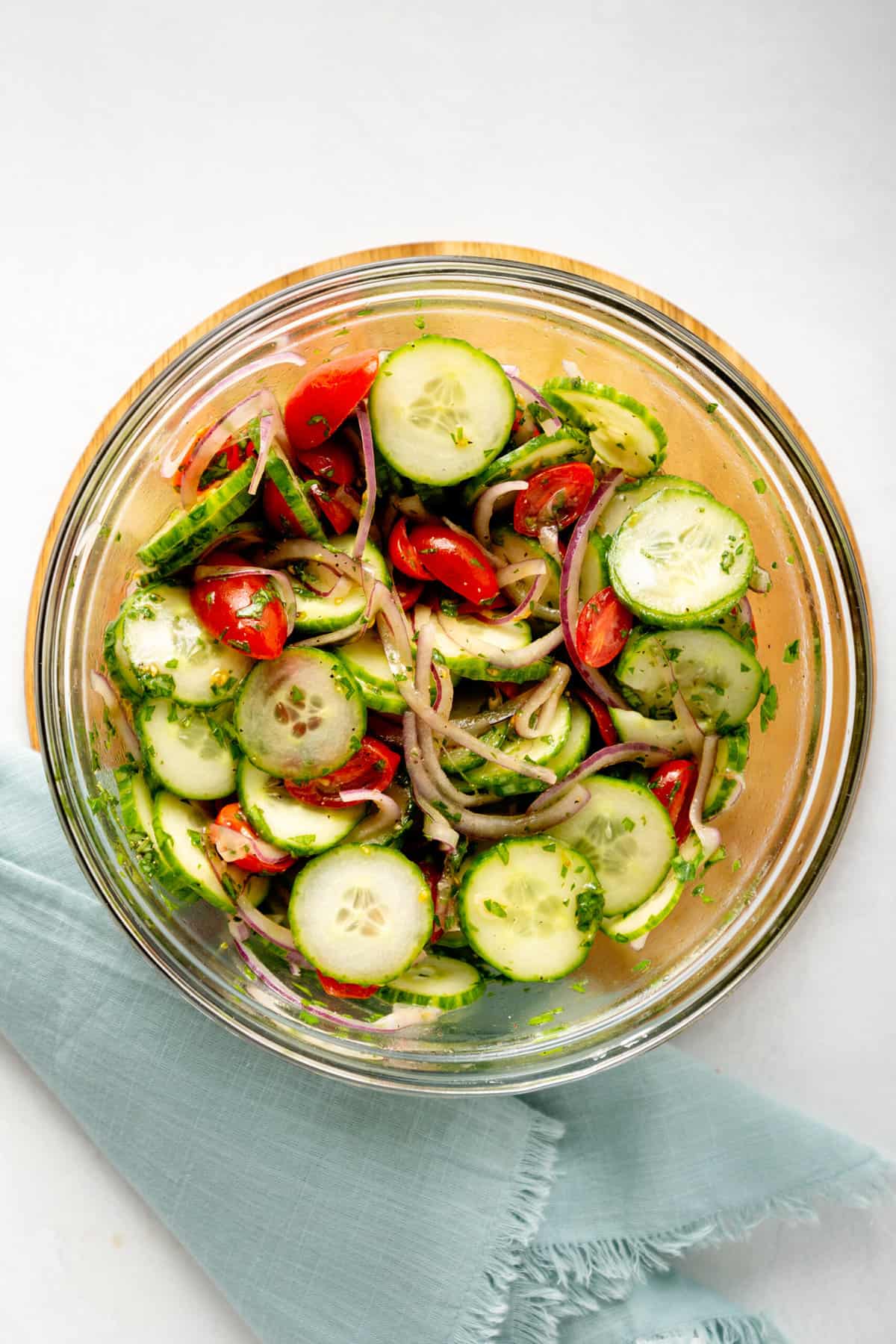 top down image of a large glass bowl of cucumber tomato salad