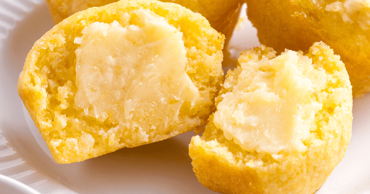 A homemade corn muffin split in half and topped with butter. 