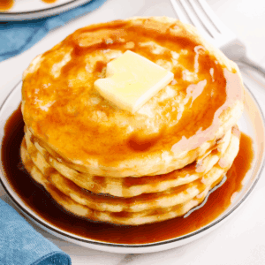 A stack of overnight pancakes topped with butter and syrup.