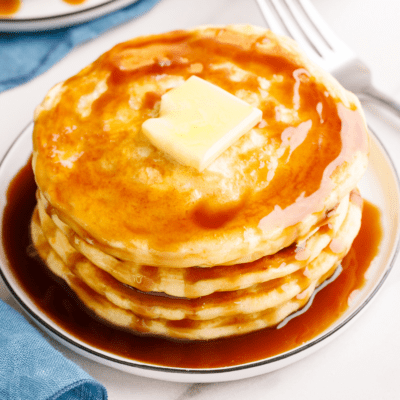 A stack of overnight pancakes topped with butter and syrup.