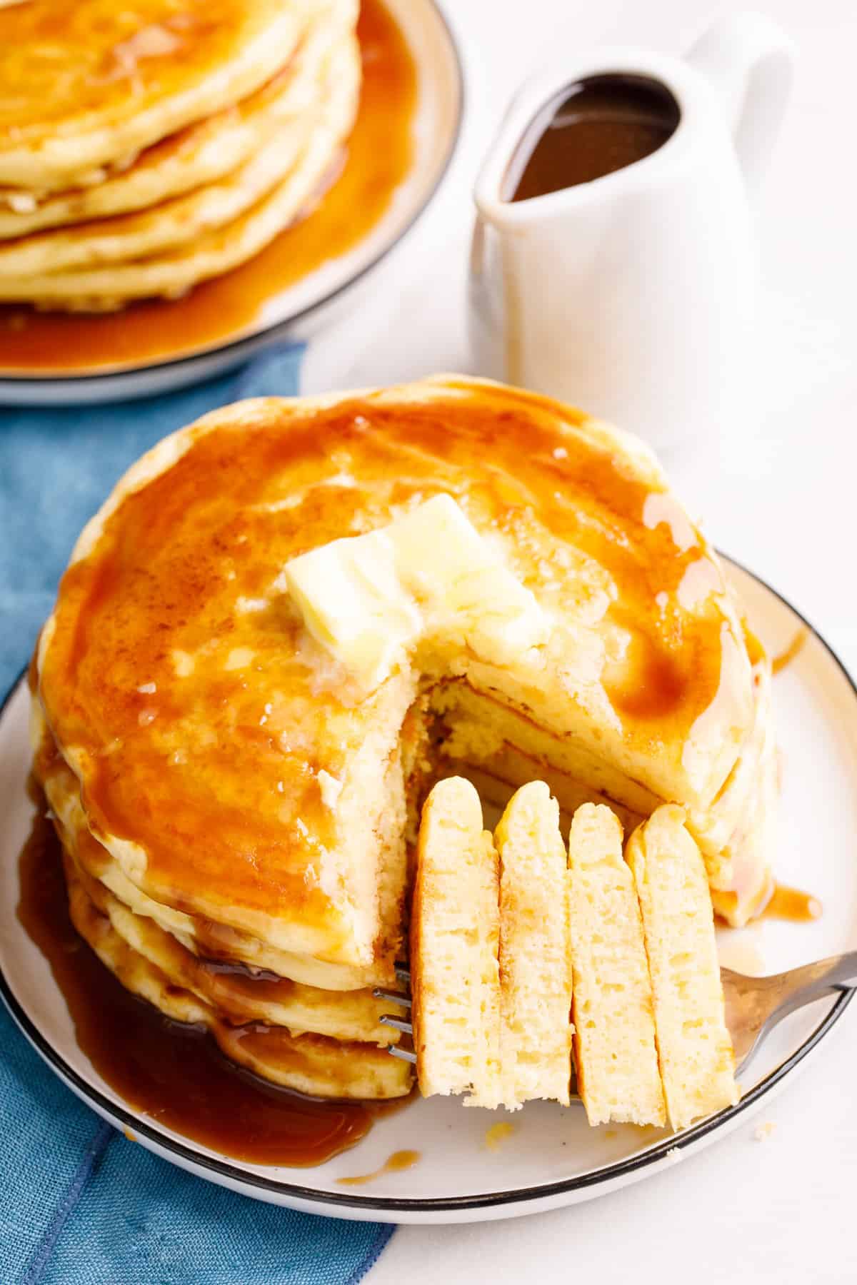 stack of four pancakes with syrup and butter cut into to show the cross section