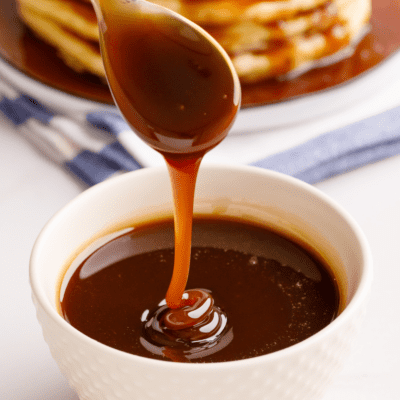 A bowl of homemade pancake syrup with a spoon lifting a scoop.