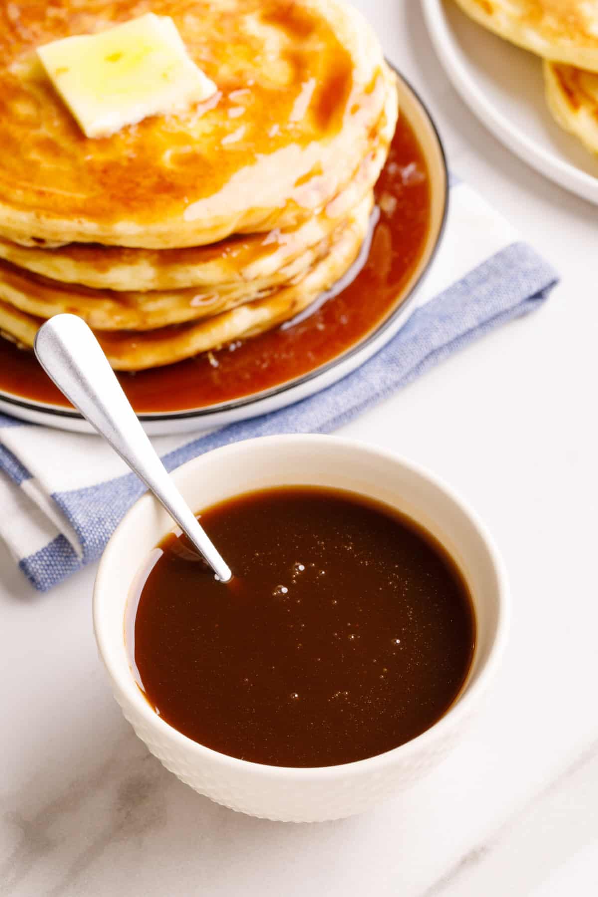 white bowl of homemade pancake syrup with a spoon sitting in the bowl