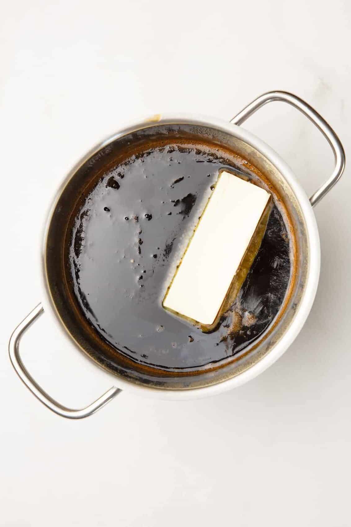 pancake syrup in a stainless steel sauce pan with a stick of butter