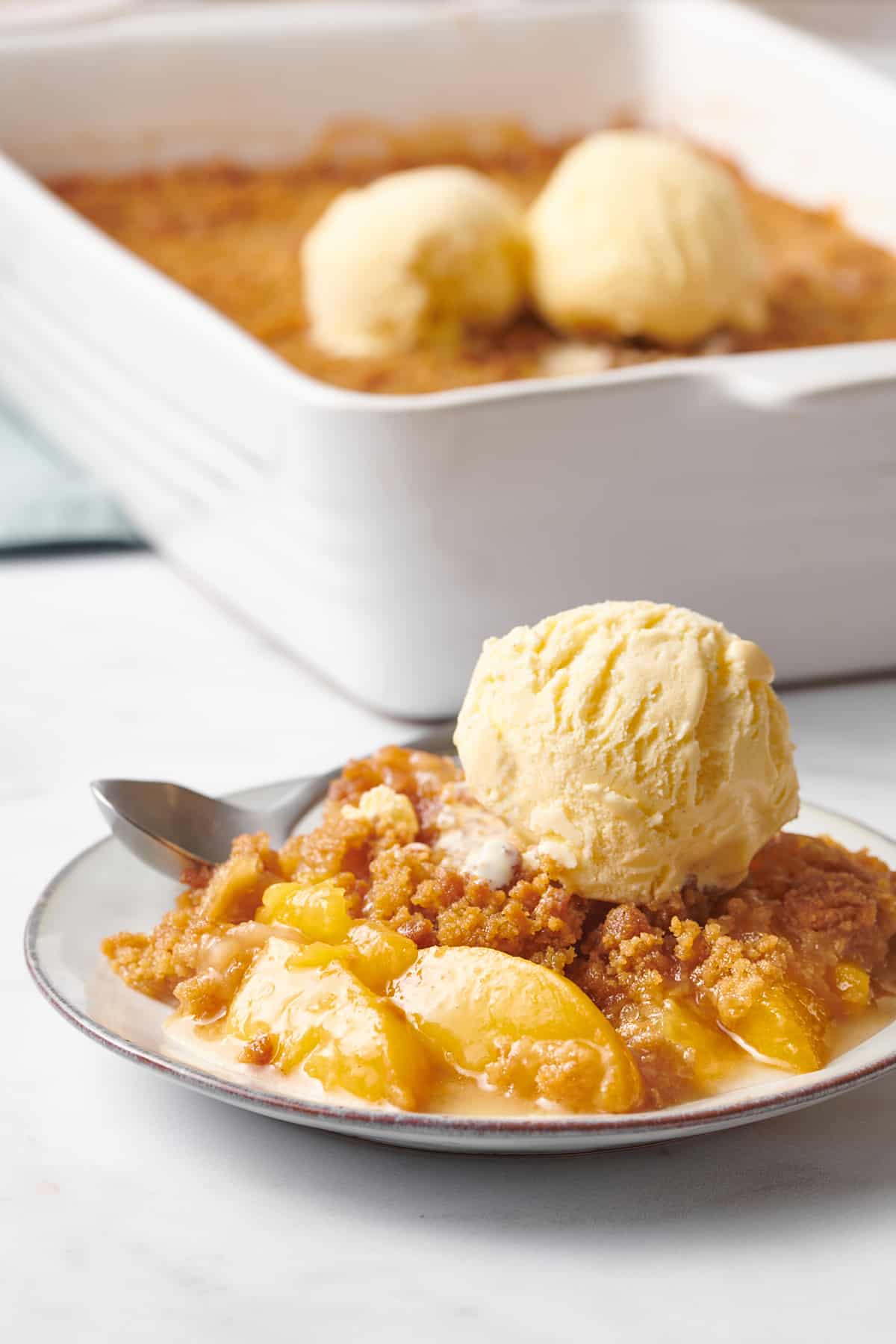plate of peach crumble topped with a scoop of vanilla ice cream