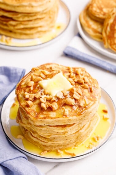 A stack of peanut butter waffles topped with peanuts and butter.