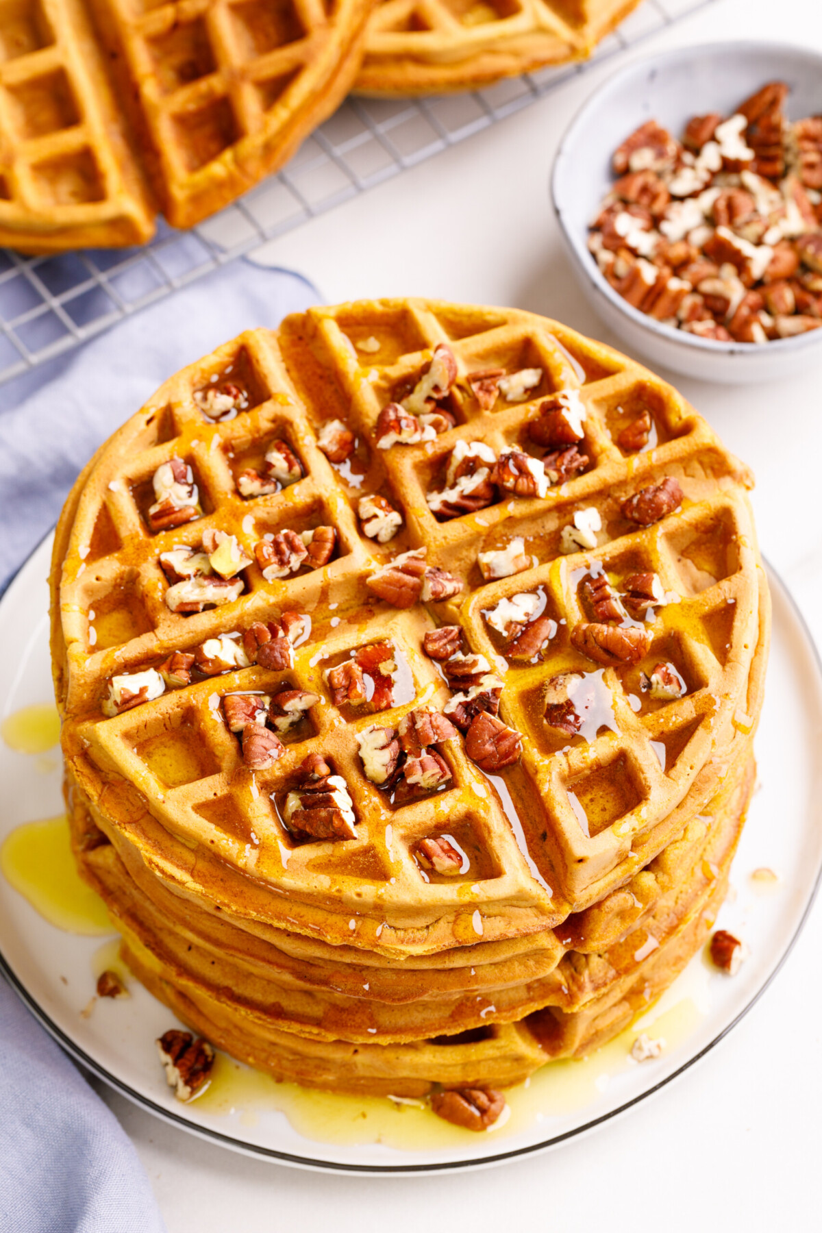 A large stack of sweet potato waffles with pecans on top. 