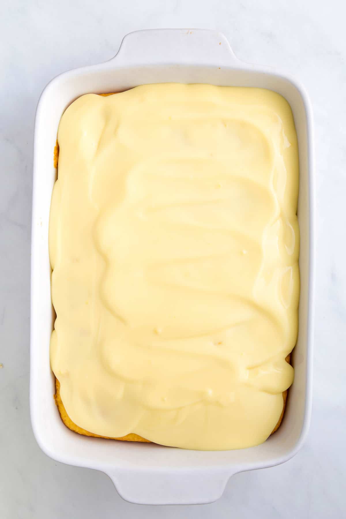 banana pudding mix layered on top of poked vanilla cake