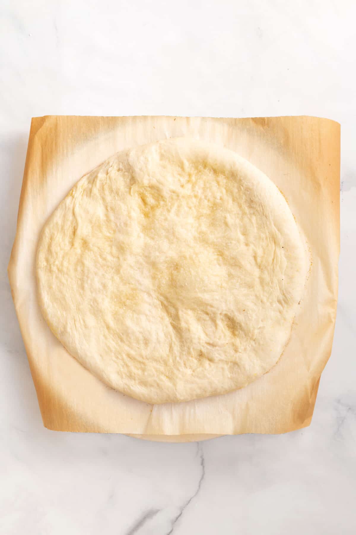 parbaked pizza crust sitting on parchment paper.