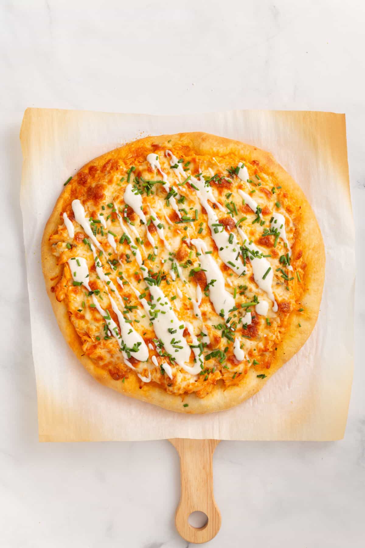 cooked buffalo chicken pizza sitting on parchment paper.
