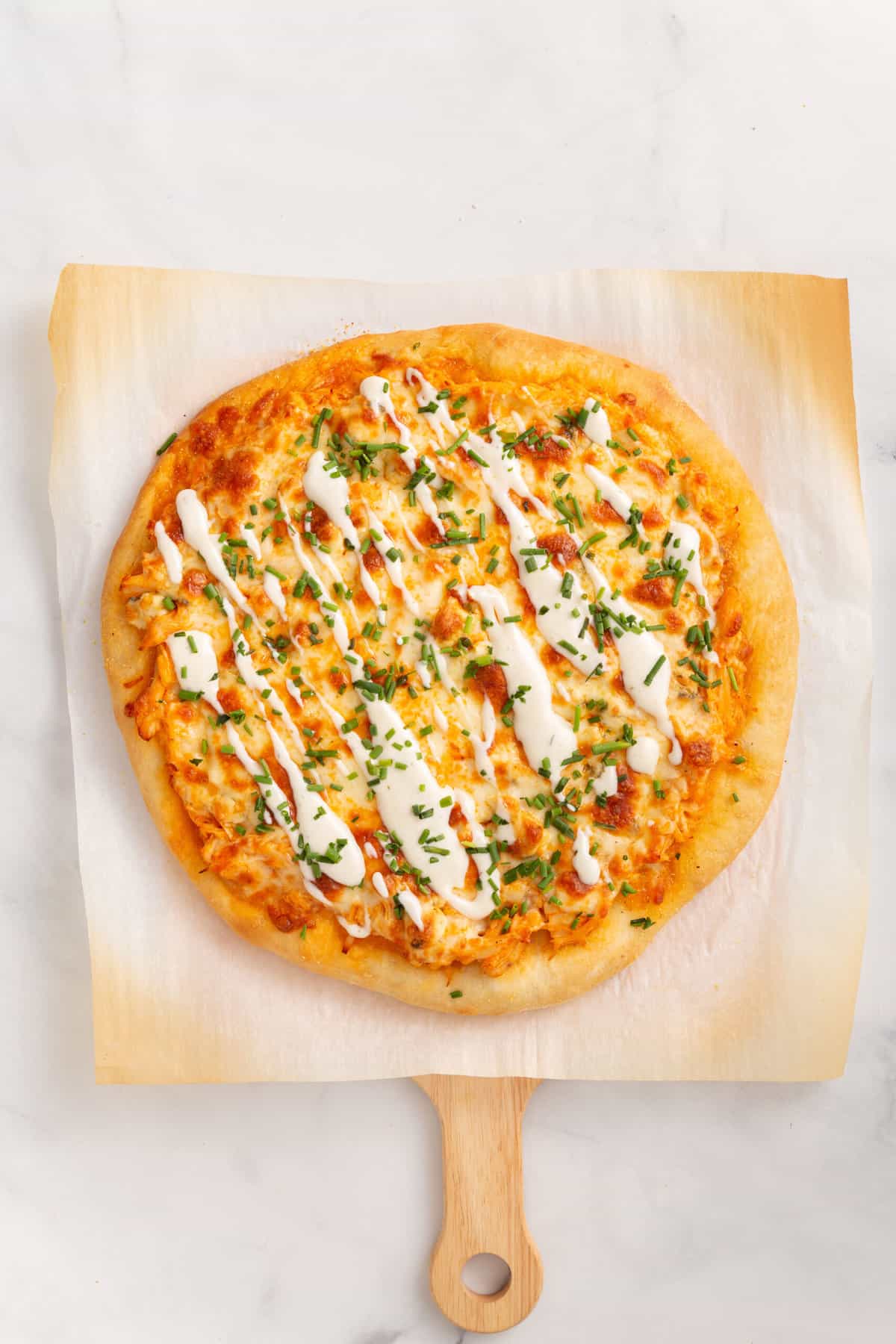 cooked buffalo chicken pizza sitting on parchment paper