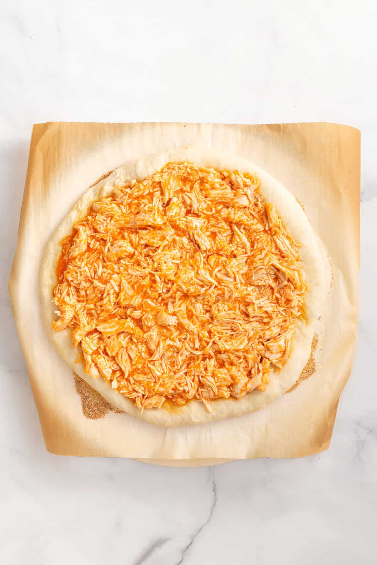 parbaked pizza crust with buffalo chicken mixture on top