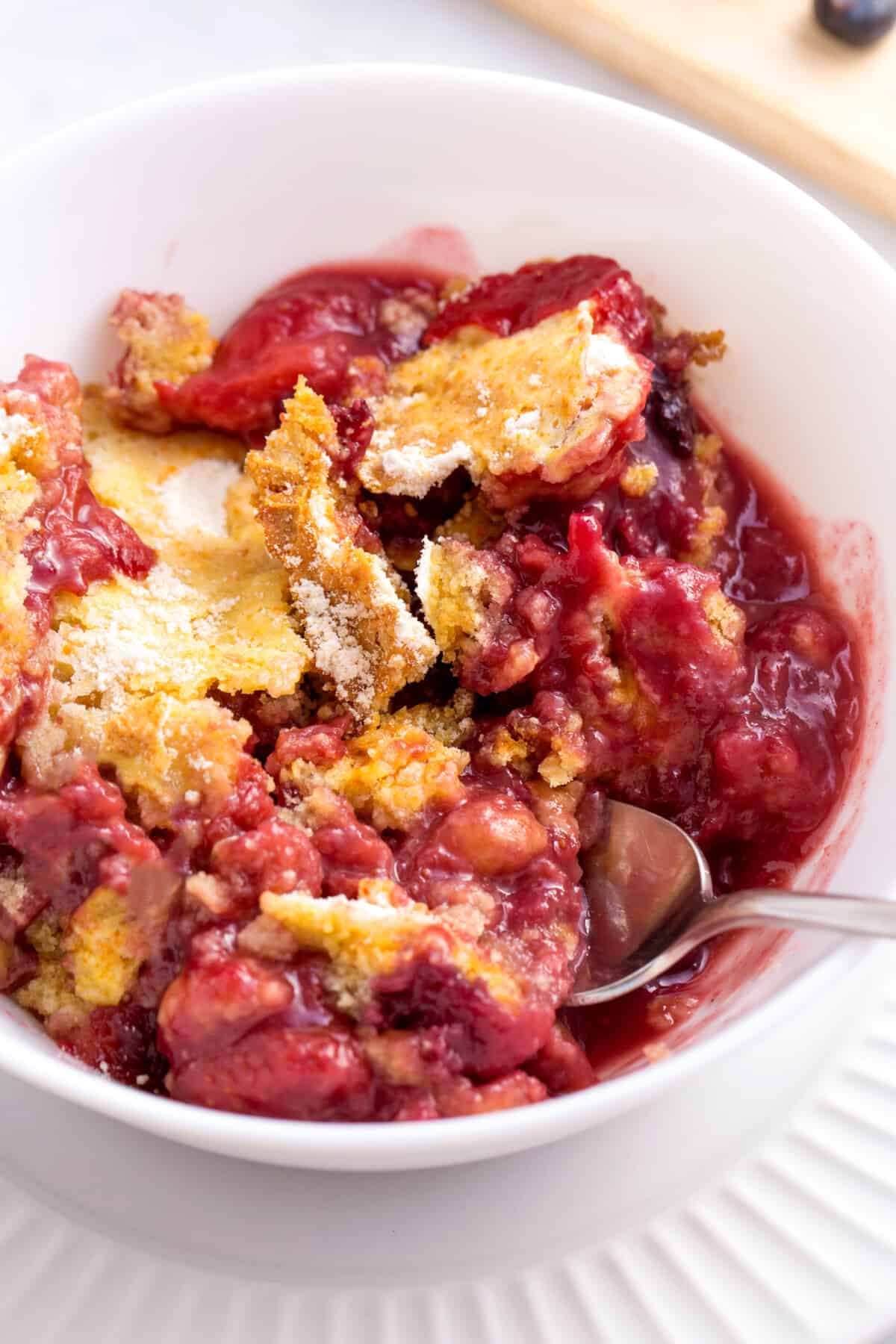 A bowl of mixed berry cobbler with a spoon sticking out.