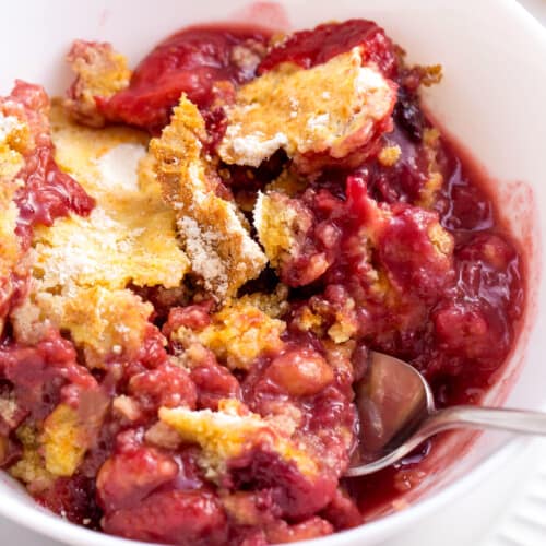 A bowl of mixed berry cobbler with a spoon sticking out.
