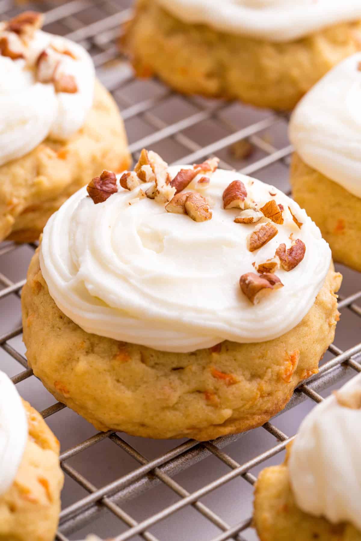 close up image of a carrot cake cookie frosted with cream cheese frosting and chopped pecans