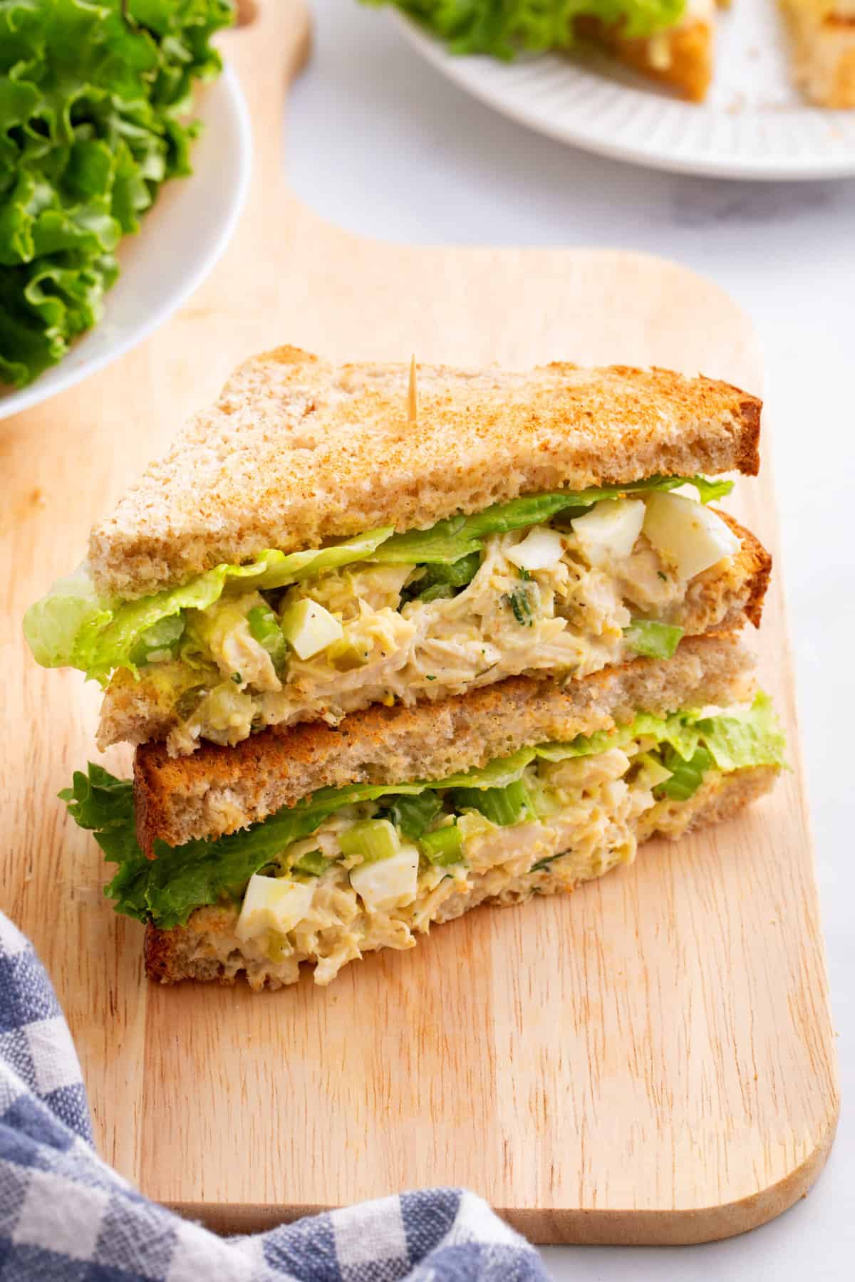 Chick Fil A Chicken Salad sandwich cut in half stacked and sitting on a wood board