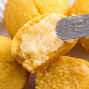 Butter being spread over a cornbread muffin.
