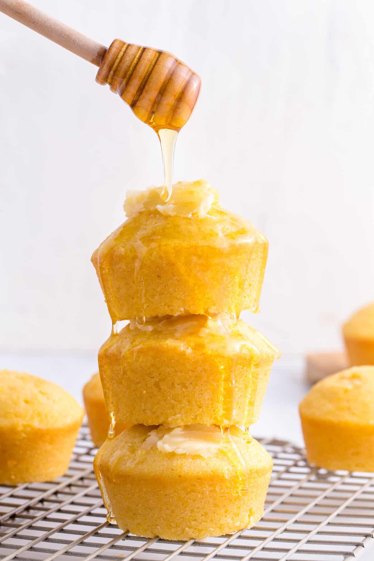 honey drizzled over a stack of three homemade corn muffins topped with honey butter