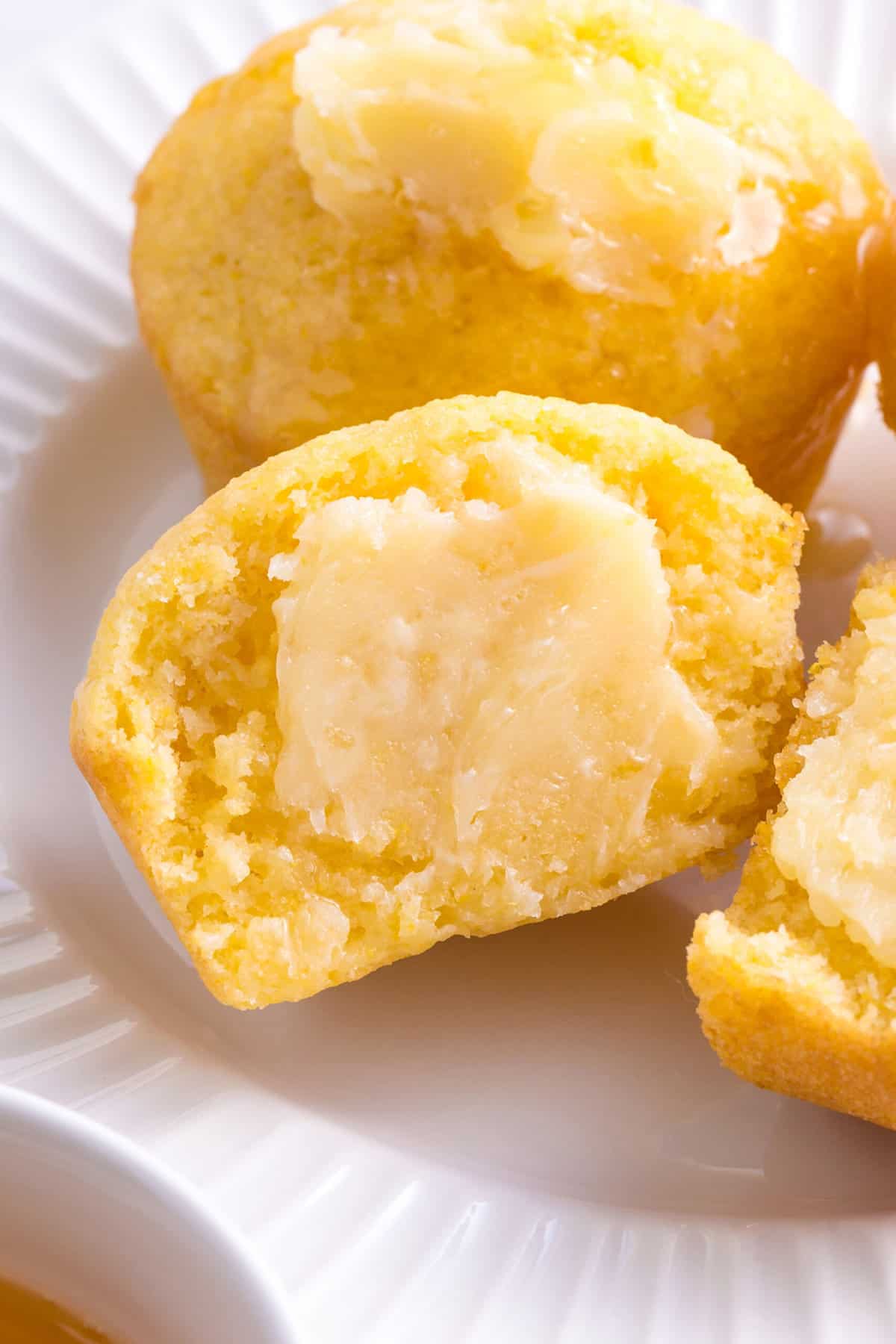 close up image of homemade corn muffins halved and spread with homemade honey butter