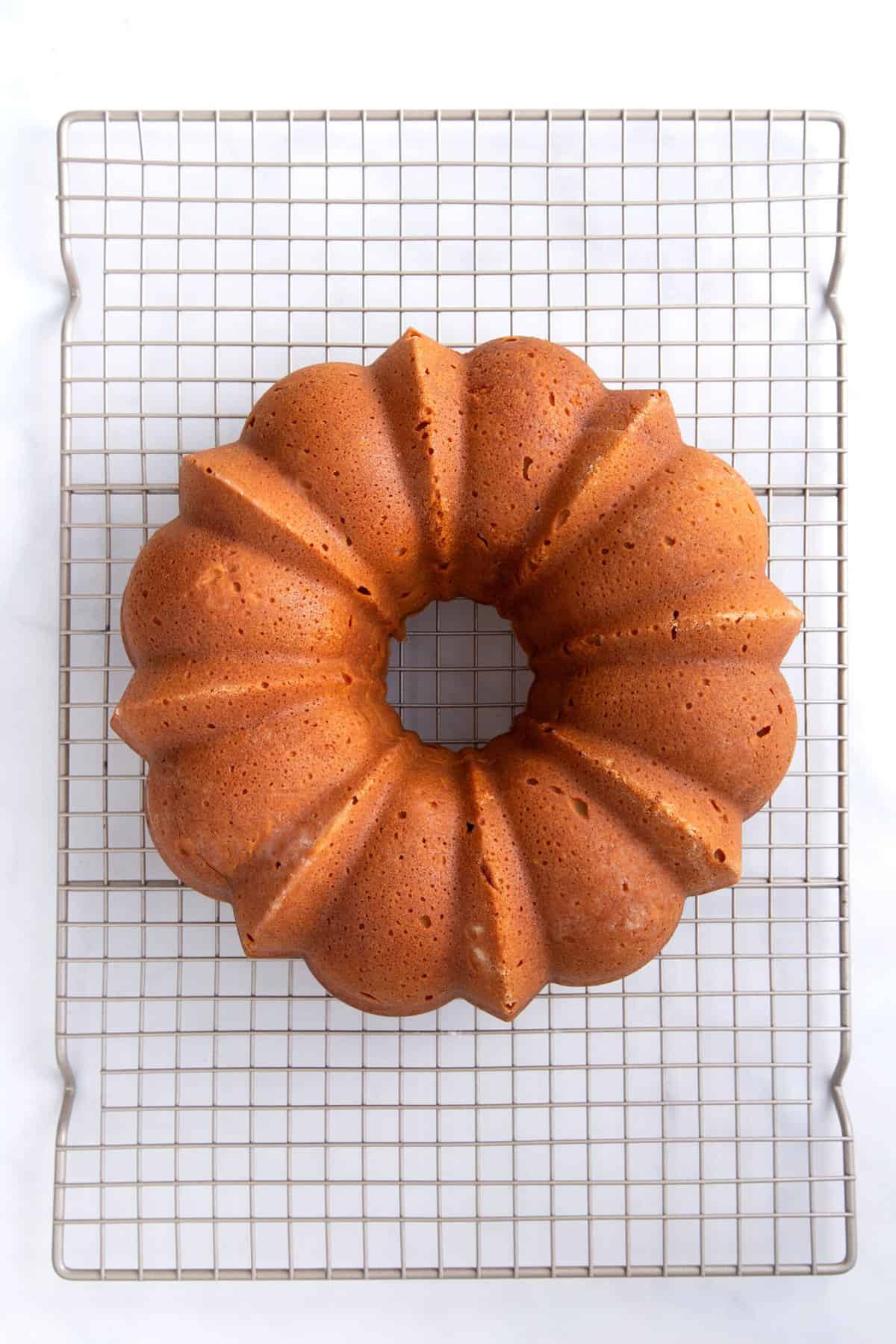 cream cheese pound cake in a bundt shape cooling on a metal wire rack