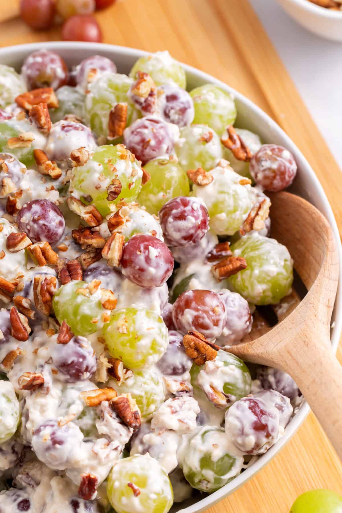 close up image of a large bowl of grape salad topped with chopped pecans