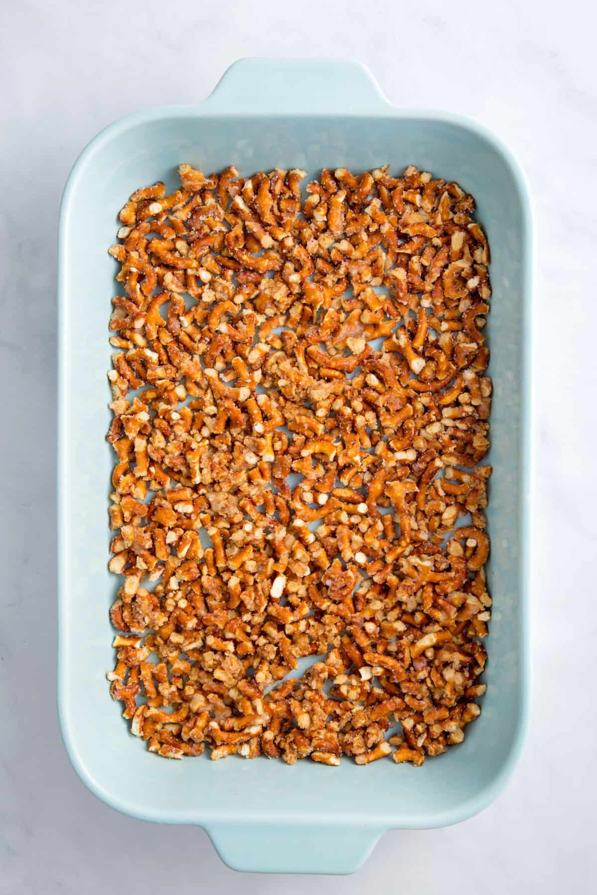 crushed pretzels in a large blue casserole dish