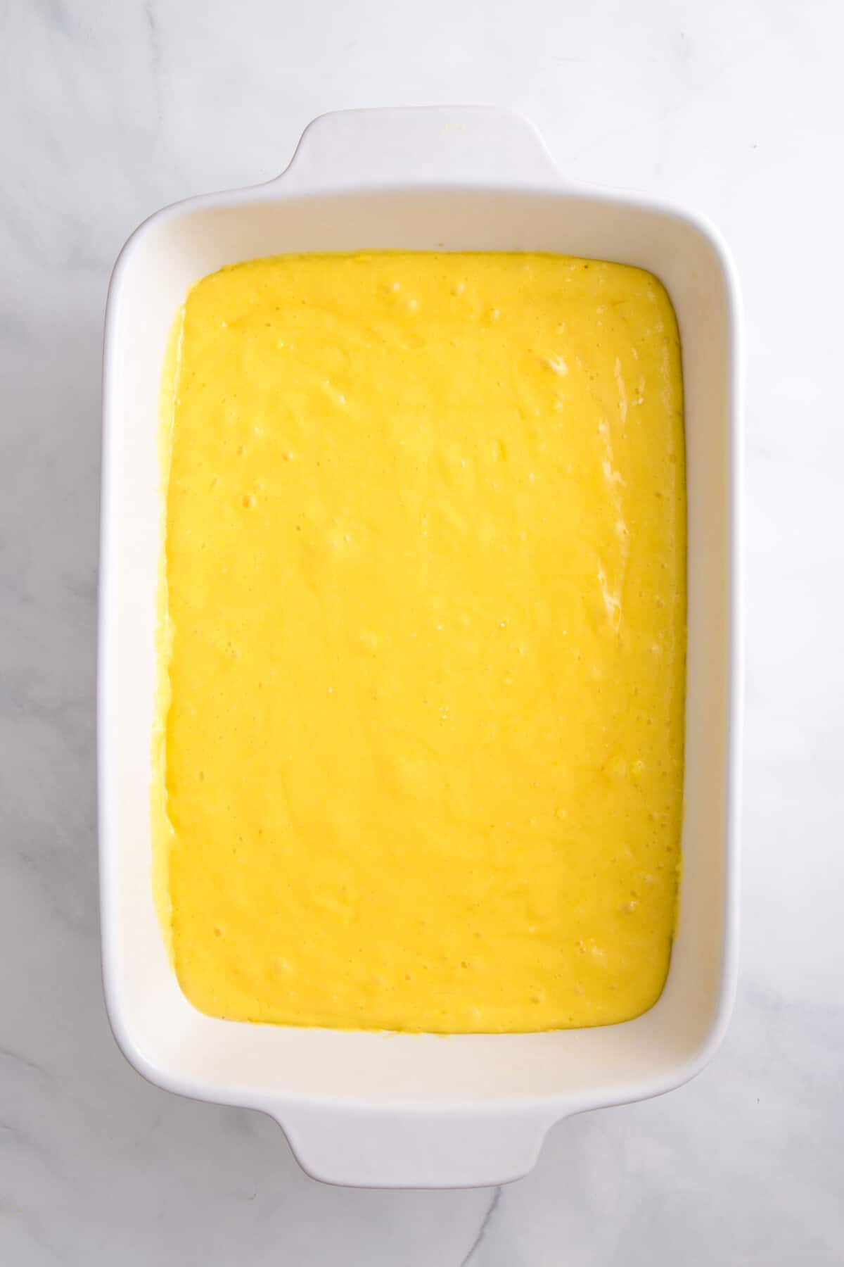 lemonade cake batter sitting in a 9x13 casserole baking dish.