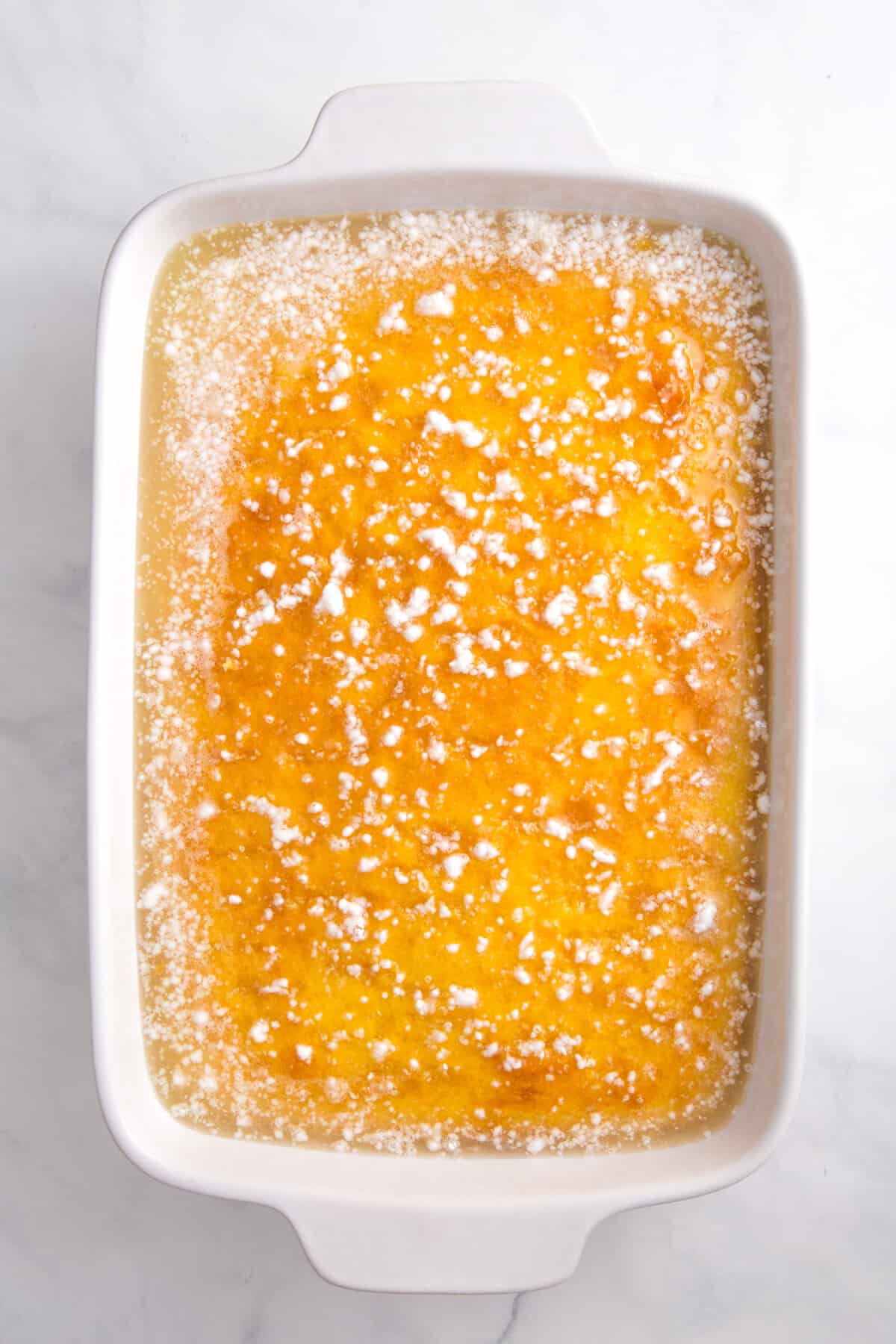 baked lemonade cake sitting in a 9x13 casserole baking dish.