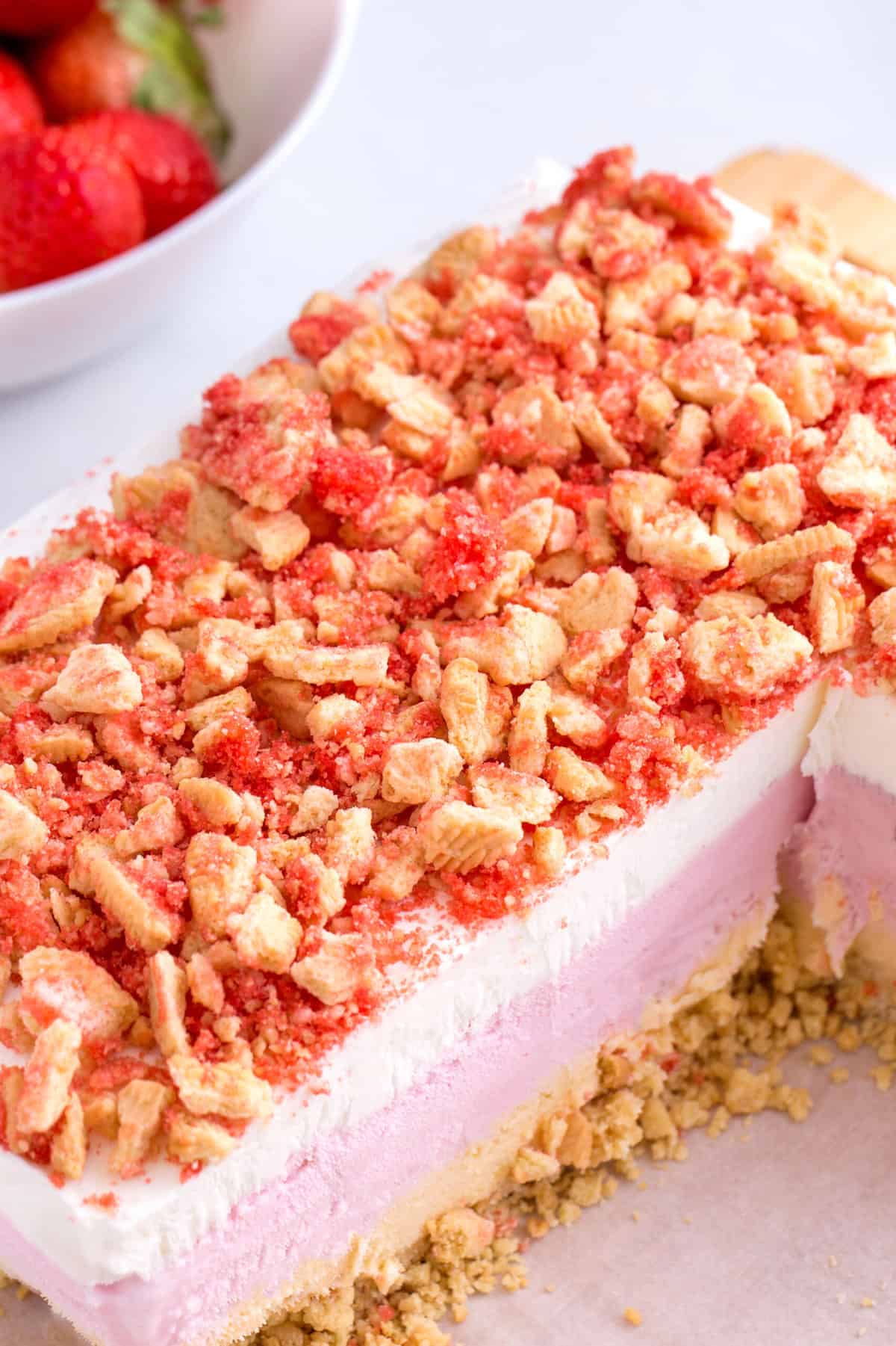 strawberry crunch ice cream cake cut into to show the cross section and all the ice cream and crunch layers