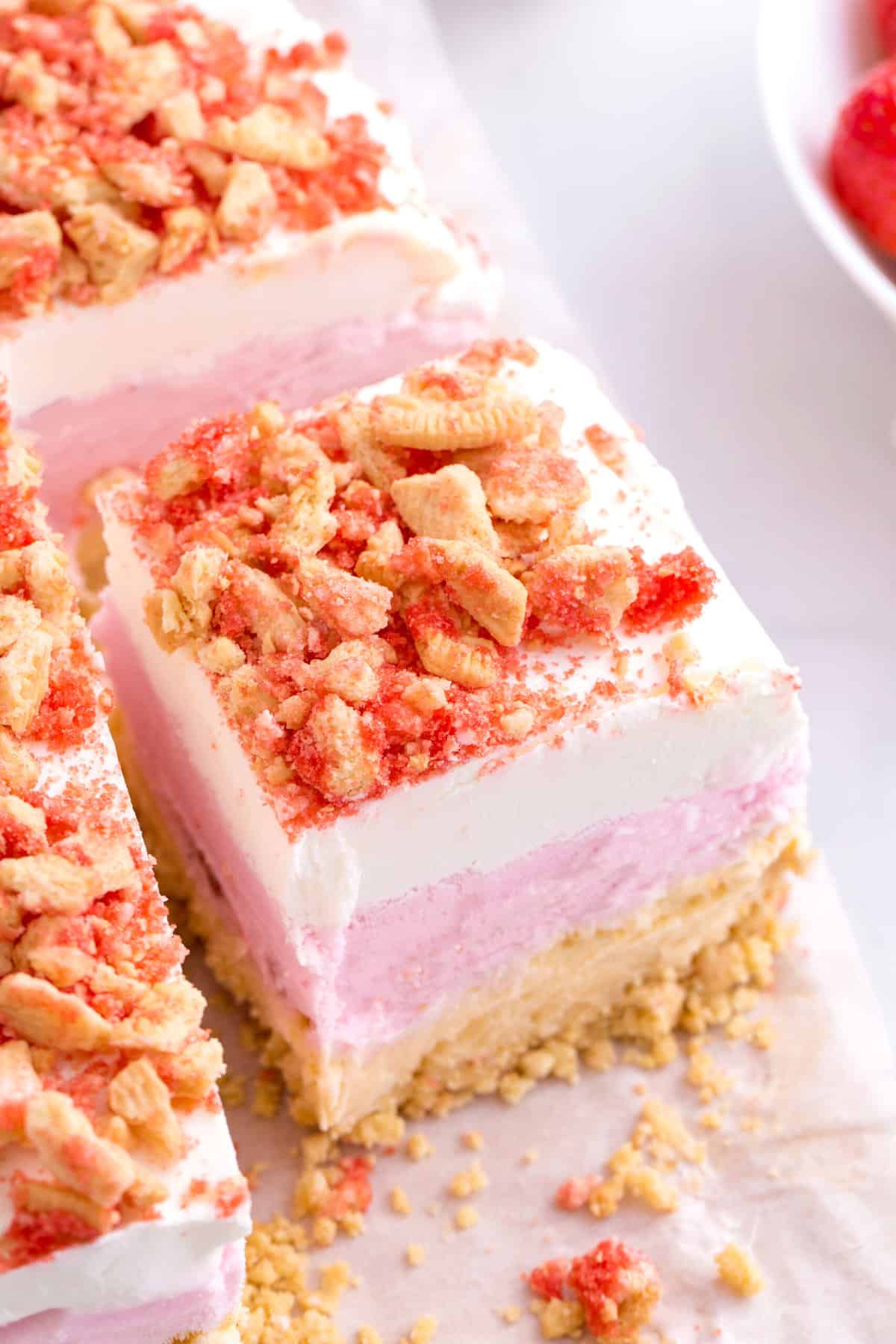 close up image of a square serving of strawberry crunch ice cream cake