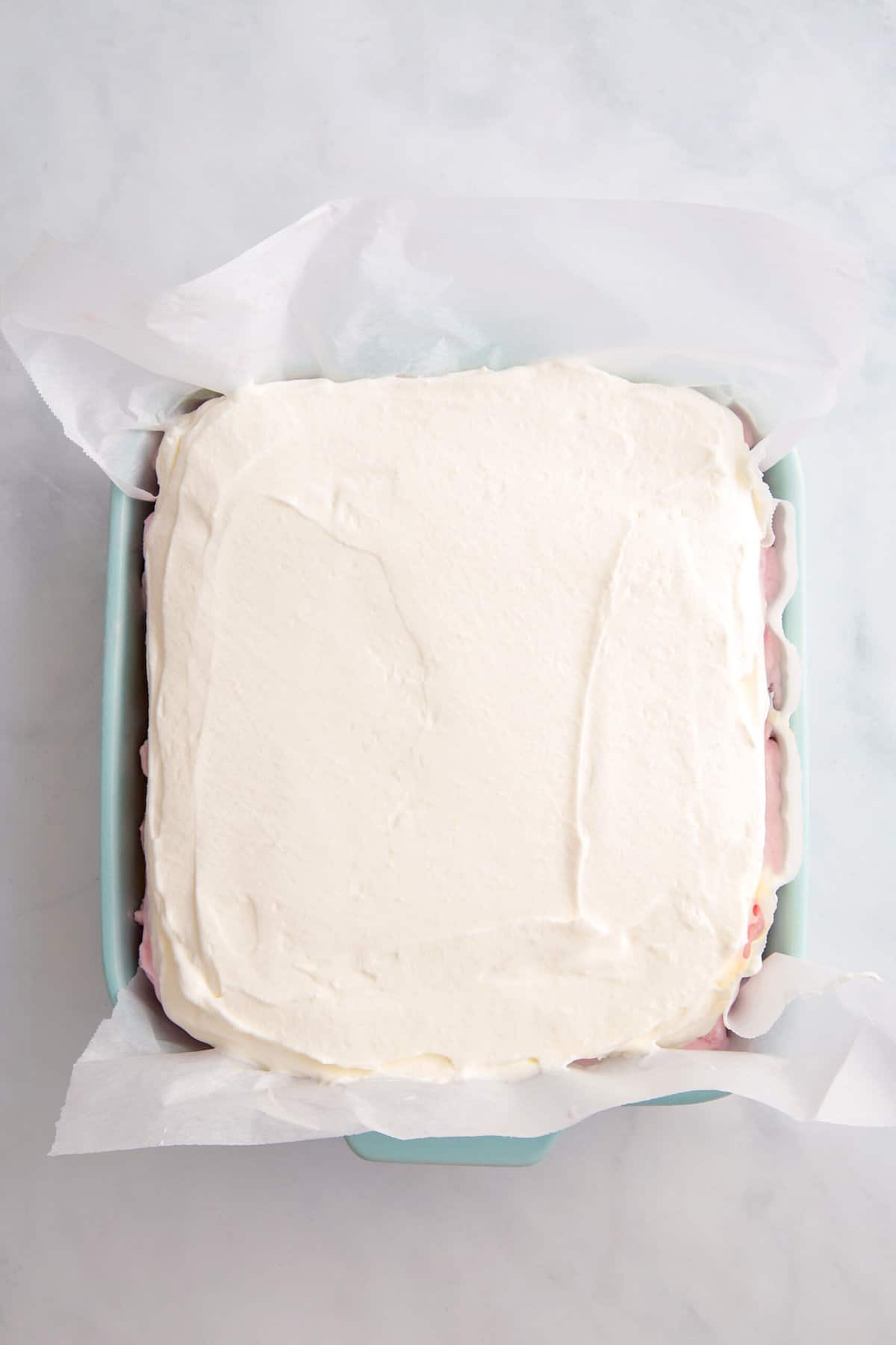 vanilla ice cream layered on top of an 8x8 dish to make strawberry crunch ice cream cake