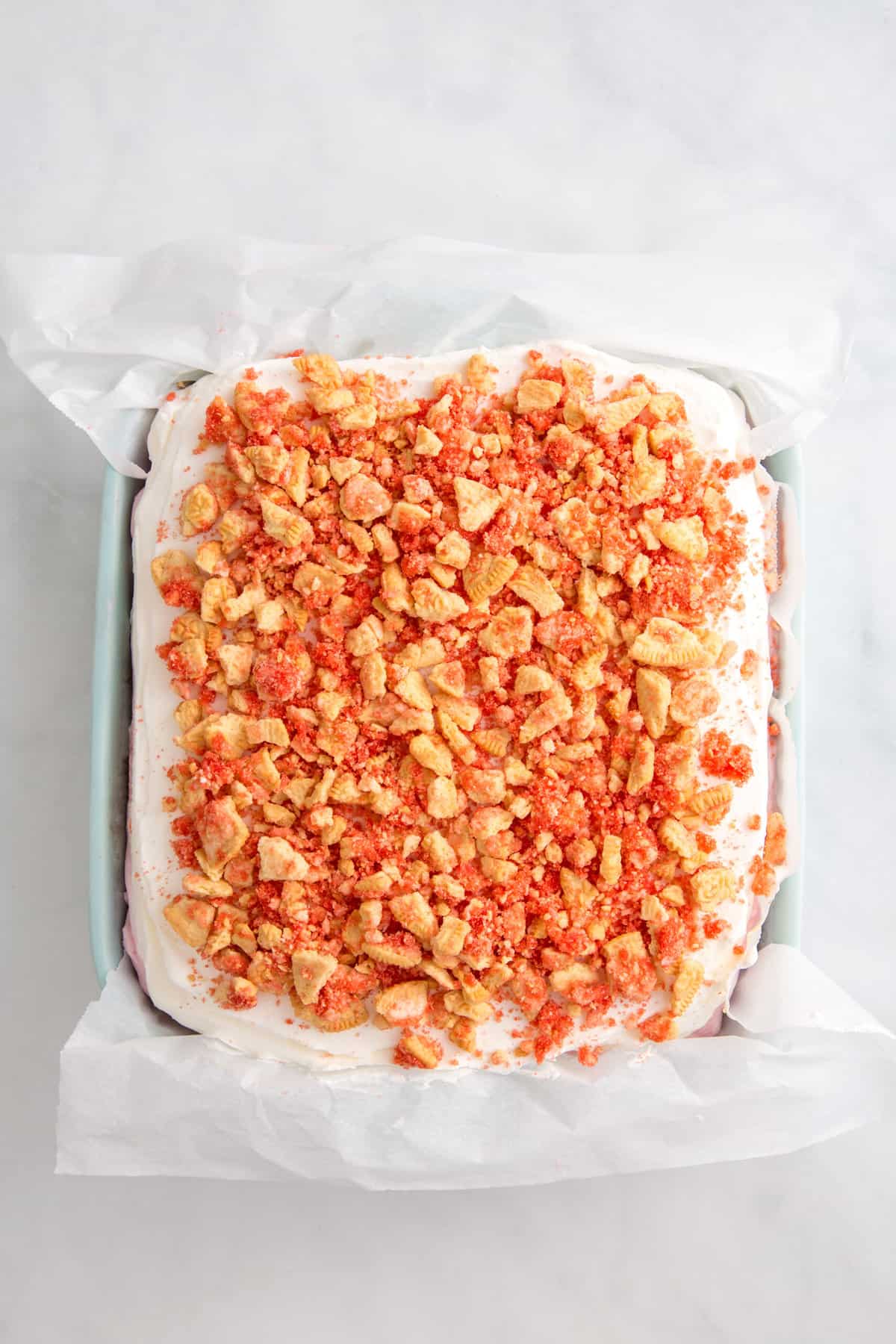 all the layers of strawberry crunch ice cream cake assembled in an 8x8 dish