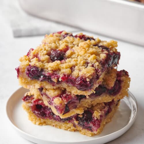 Three blueberry crumble bars on a plate.