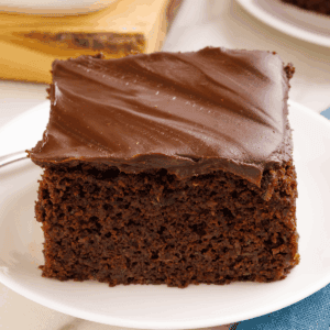 A slice of chocolate zucchini cake topped with ganache on a plate.