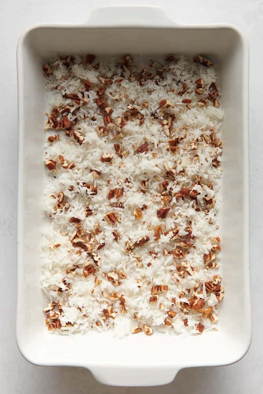 chopped pecans and shredded coconut at the bottom of a 9x13 casserole dish