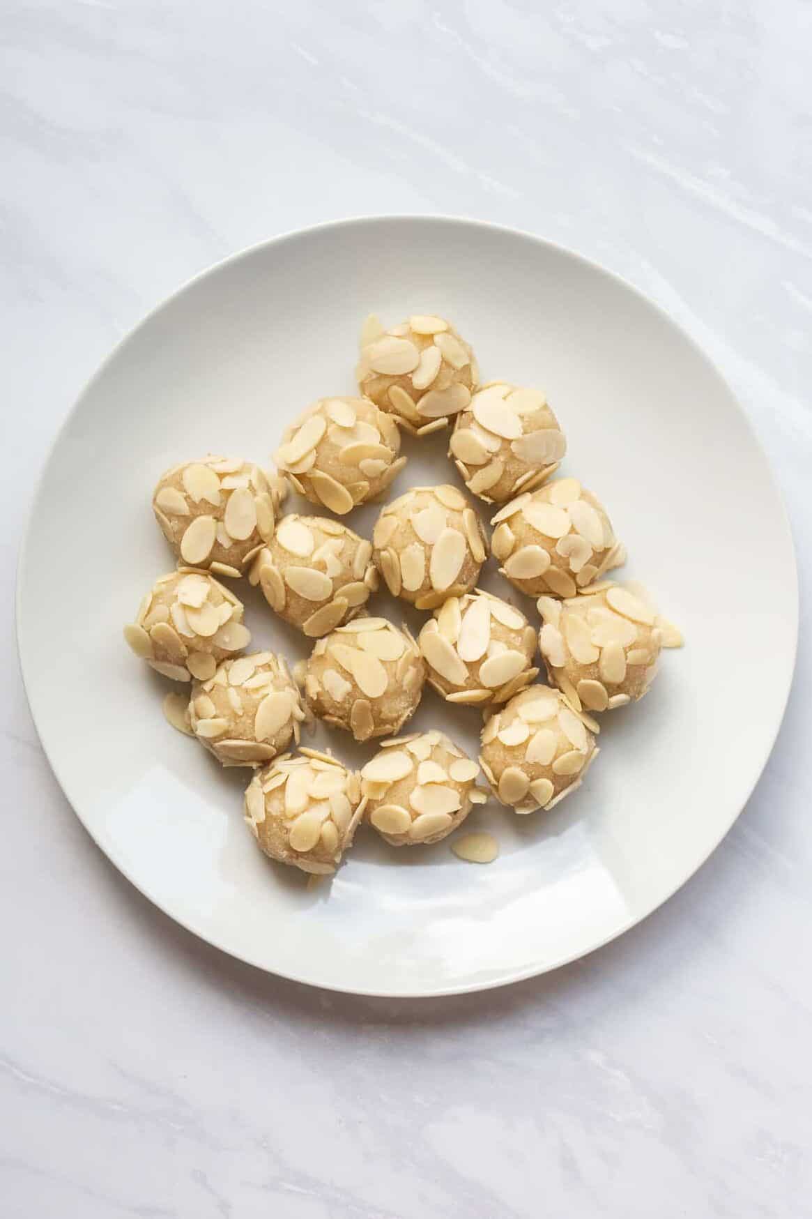 white plate of prepared almond cookie dough balls.