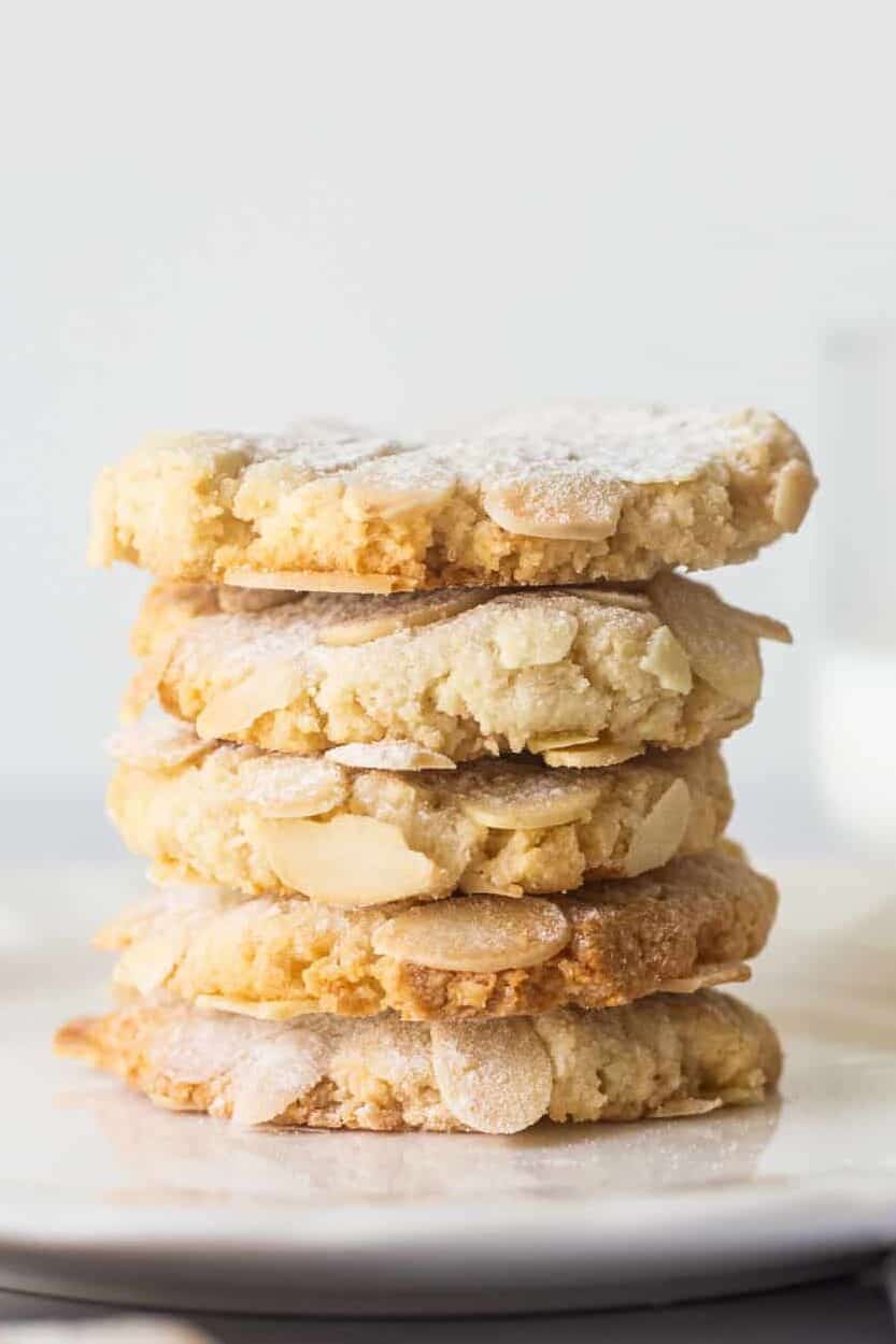 stack of five almond cookies sitting on a white round plate