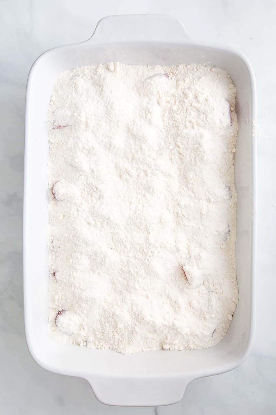 yellow cake mix layered on top of frozen berries and brown sugar in a 9x13 casserole dish