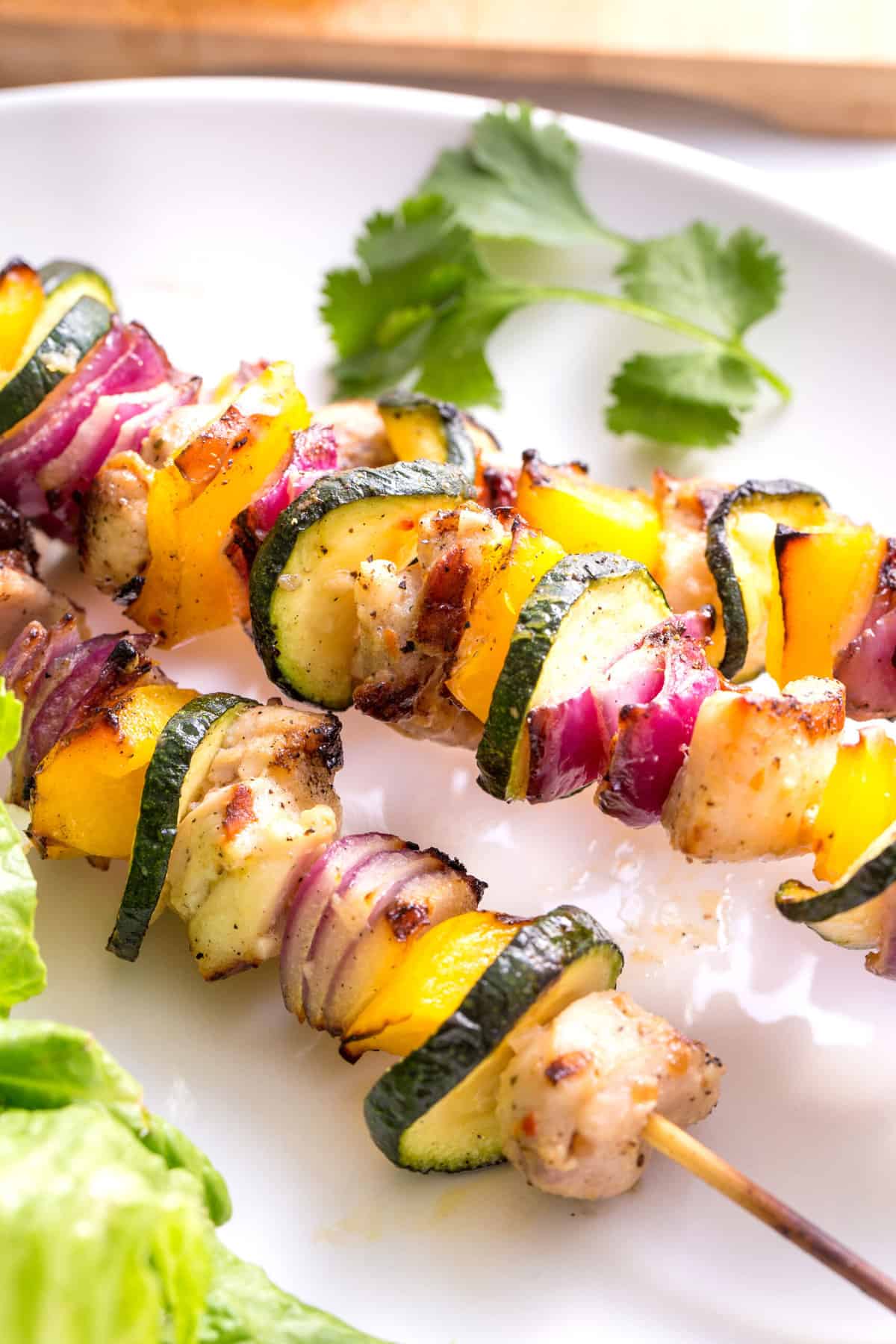close up image of three grilled chicken and vegetable kabobs