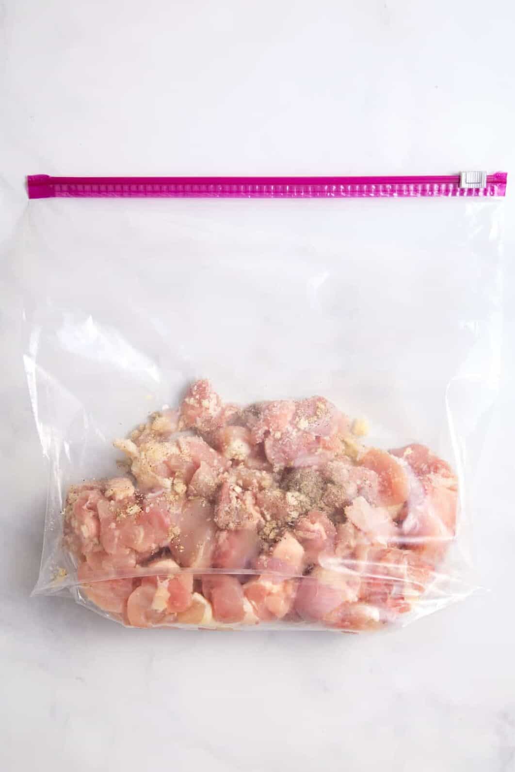 cubed chicken in a ziploc bag with seasonings