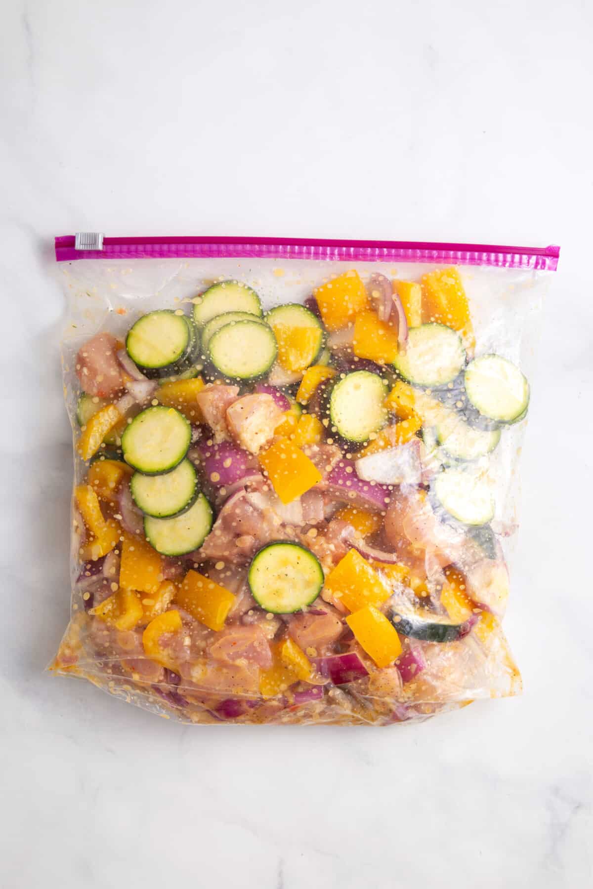 Chicken and vegetables marinating in bag.