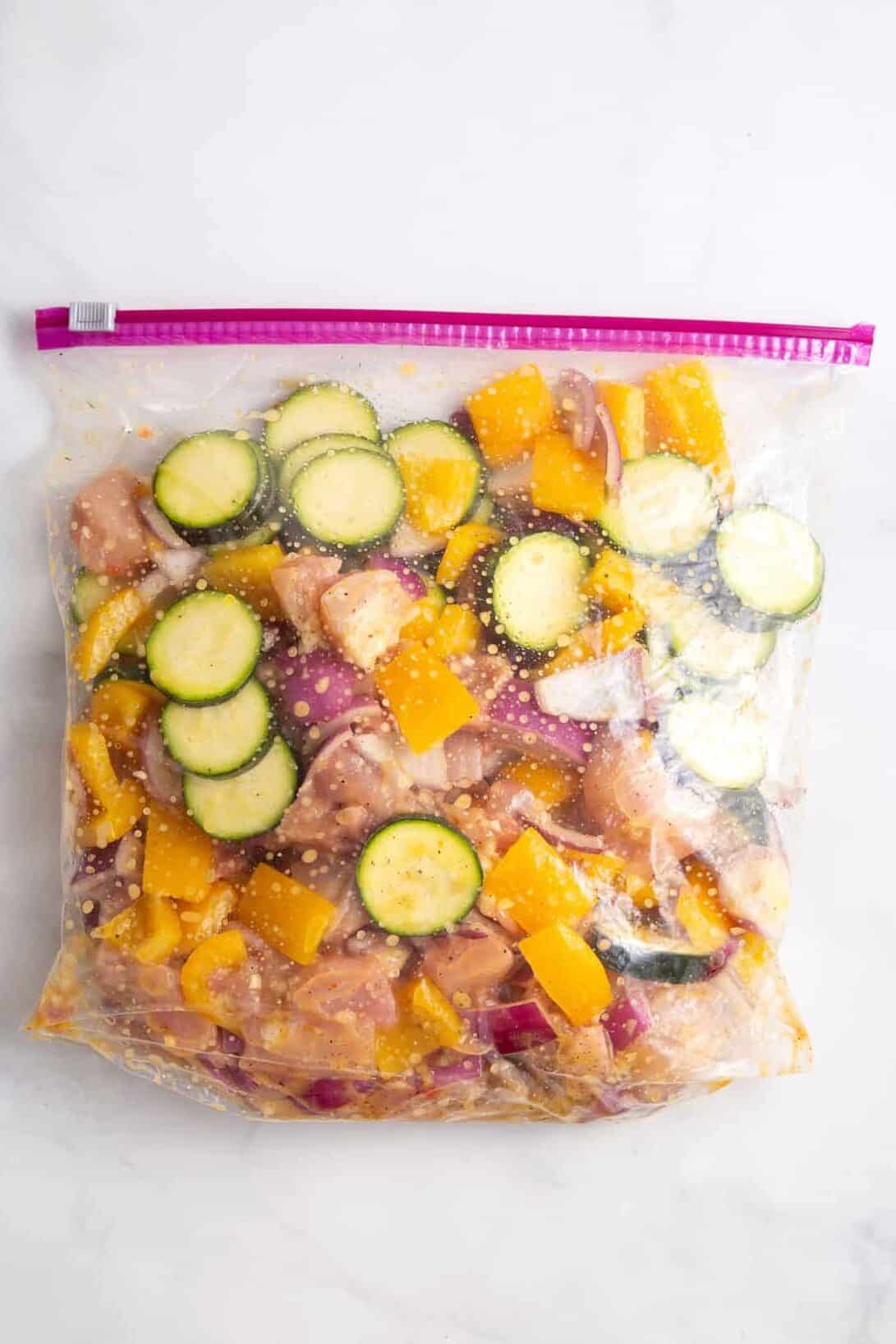 cubed chicken and cut summer vegetables in a ziploc bag with seasonings and italian dressing marinade