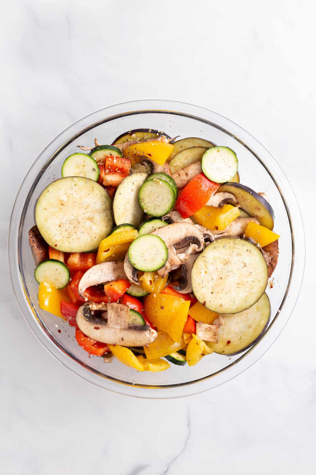 raw cut vegetables tossed in marinade sitting in a large glass bowl