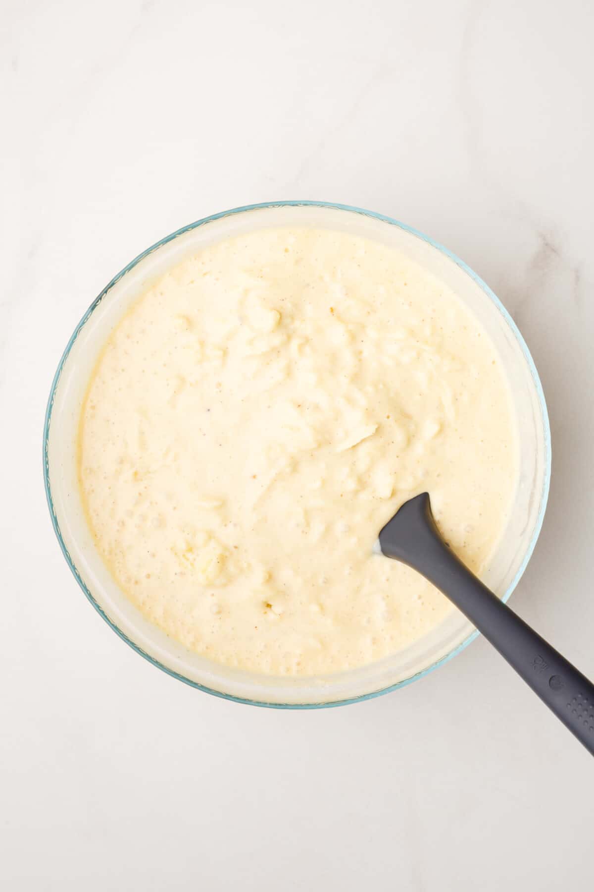 pancake batter and shredded granny smith apples combined in a large glass bowl.