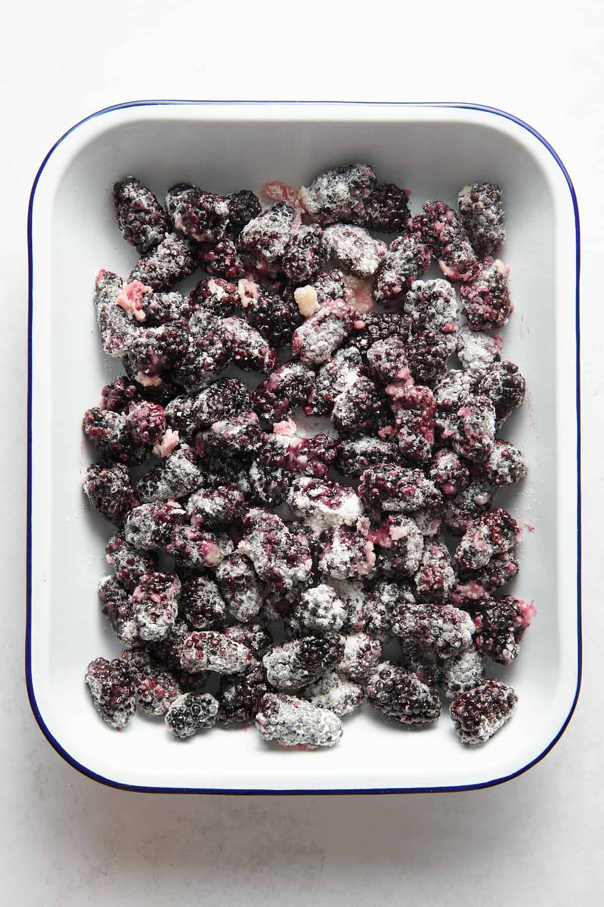 blackberries tossed and coated in a sugar, lemon, flour mixture sitting in a 9x13 baking dish