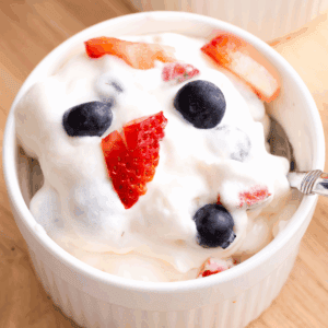 A spoon lifting a bite of red white and blue cheesecake salad from a bowl.