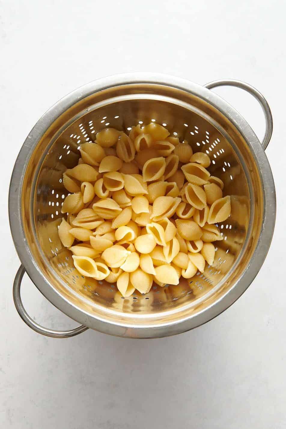 cooked shell pasta sitting in a metal colander