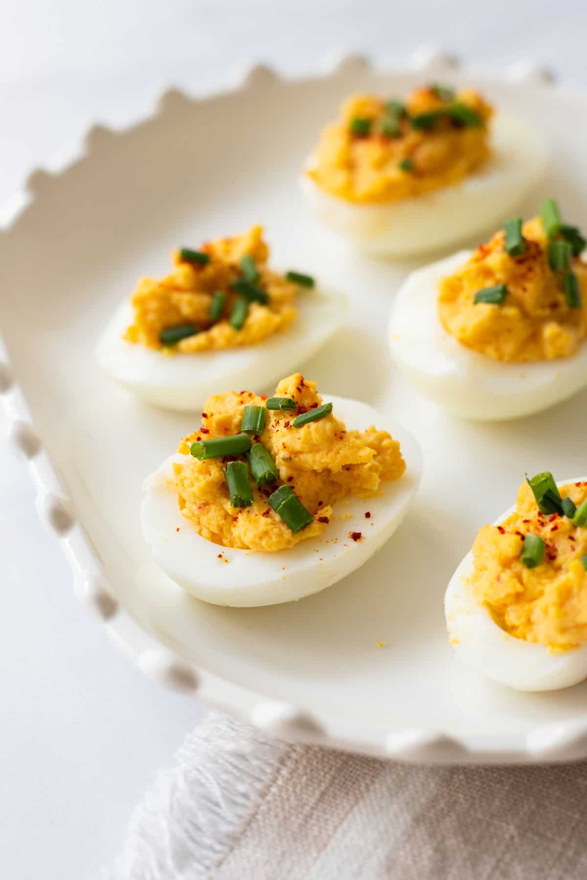 close up image of classic deviled eggs sitting on a white decorative plate